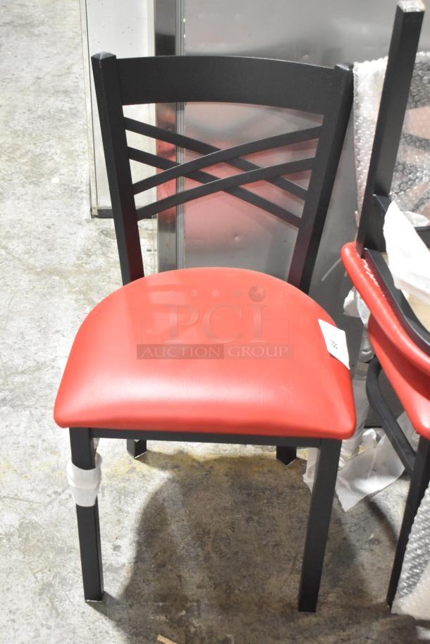 Black metal dining chair with a red cushion, featuring a crisscross back design. Auction item in good condition.
