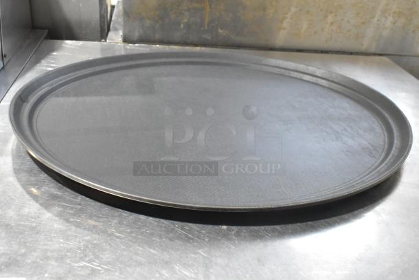 Seven black food trays, round, non-slip surface, commercial-grade. Good condition, suitable for catering or restaurant use.