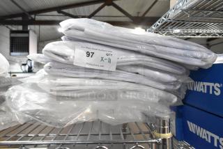 11 brand new tablecloths, model 537890RM010, 90 inches, in packaging on a metal shelf, auction quantity label visible.