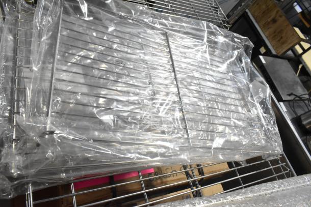 Four brand new metal racks in packaging, featuring sturdy metal construction, ideal for storage or display use.