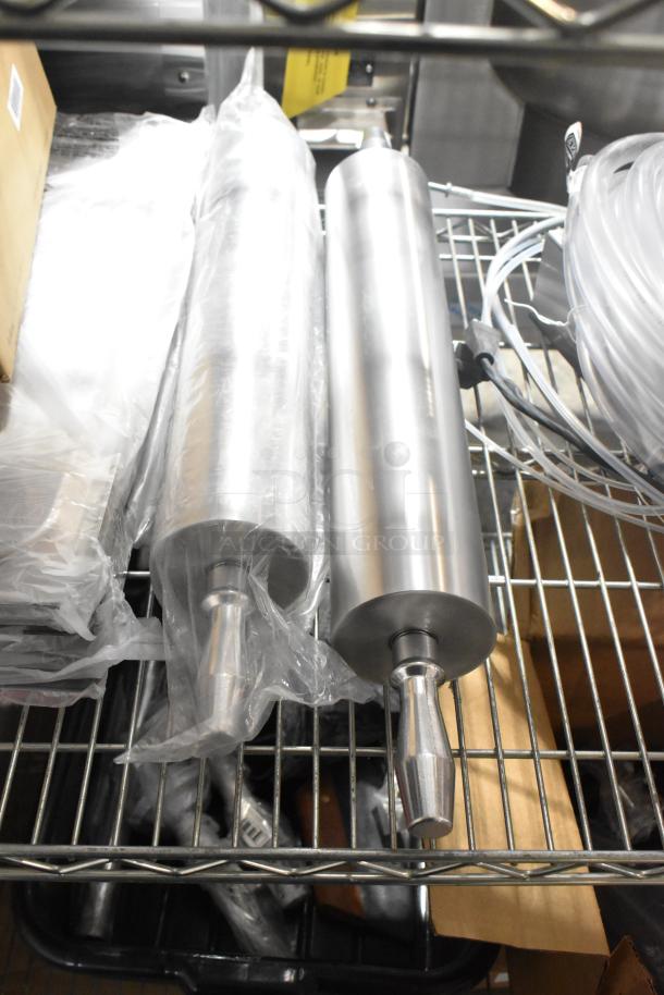 Brand new stainless steel rolling pins and drop-in bin lids on a metal shelf. Items are wrapped and unused.