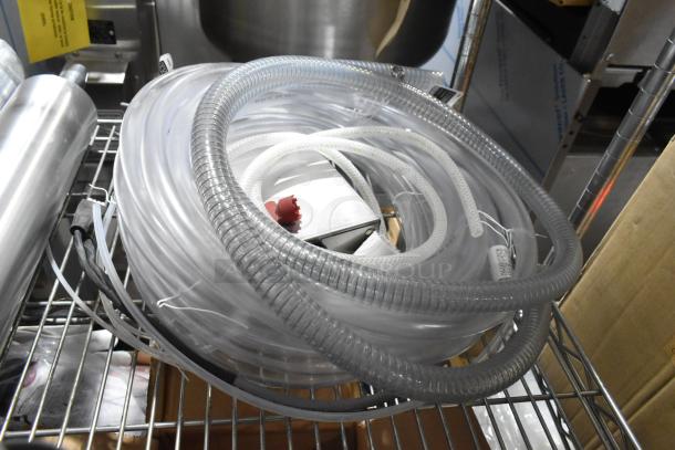 Four brand new items including Rinza Urnex tablets, Sprayon food-safe grease, and a hose, all packaged on a metal rack.