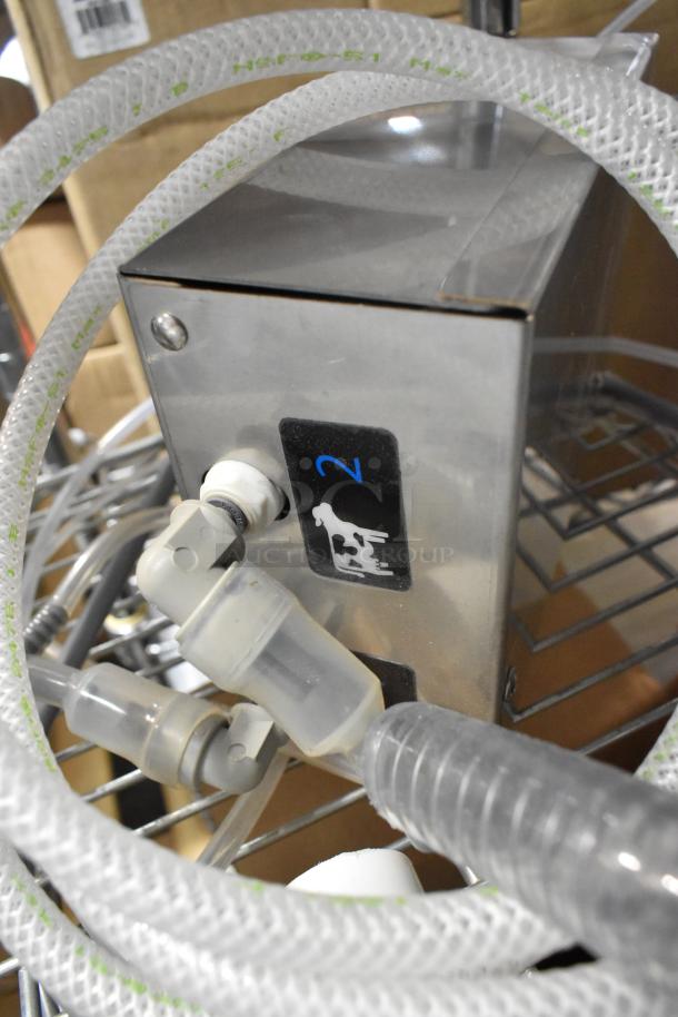 A close-up of a new stainless steel machine with attached clear hose, featuring a cow icon and the number 2 label.