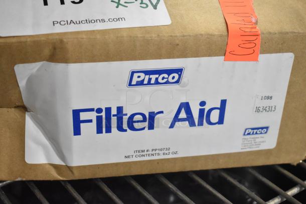 Box labeled "Pitco Filter Aid," item #PP10732. Contains 6x2 oz packets. Brand new condition. Auction tag visible.