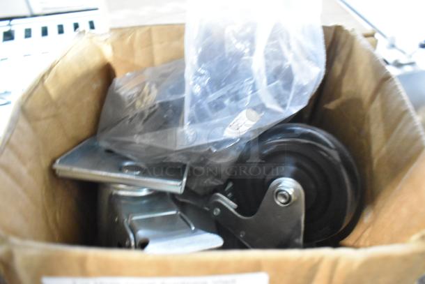 Box with two brand new Metro 5M swivel casters, metal and plastic construction, partially visible in plastic wrap.