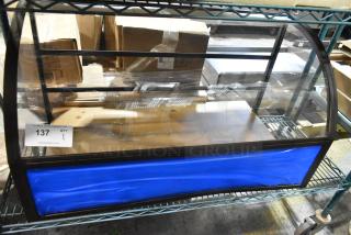 Countertop dry merchandising display case with curved glass front, black frame, and blue base panel. Auction ID tag 137.