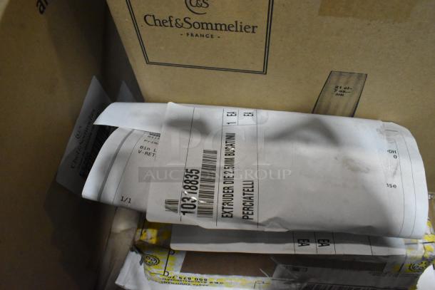 A mix of boxed and wrapped items including Chef & Sommelier packaging and labeled extruder dies. Appears new and unopened.