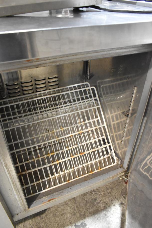 Avantco 178SSUC48FHC stainless steel undercounter freezer, 2 doors, on casters, visible wear, interior shelving, 115V, 1 phase.