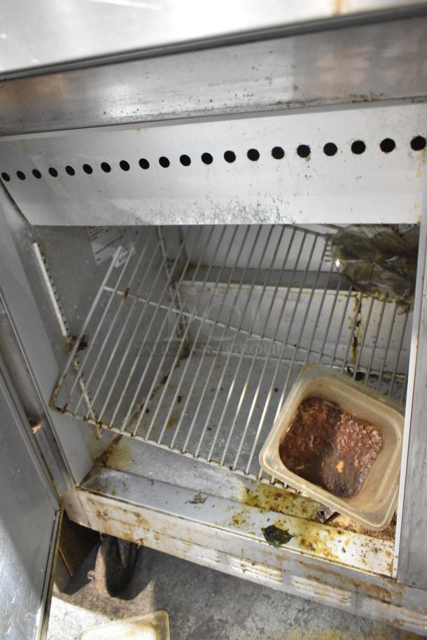 Beverage Air SP48-18M stainless steel prep table interior showing shelving, wear, and stains, indicating used condition.