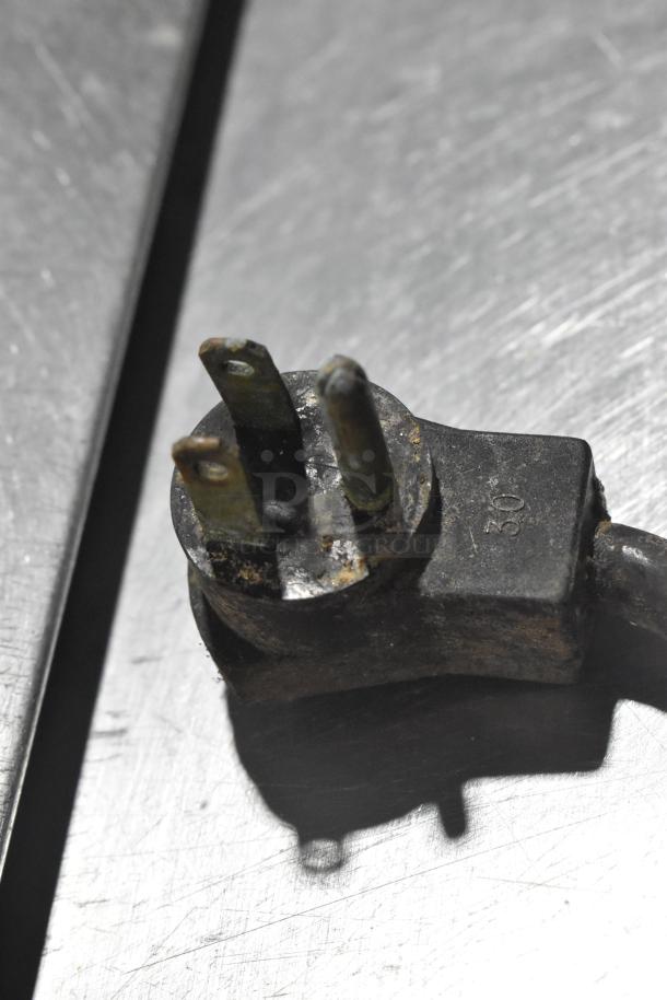 Close-up of a worn power plug on a stainless steel surface, part of Beverage Air SP48-18M prep table.