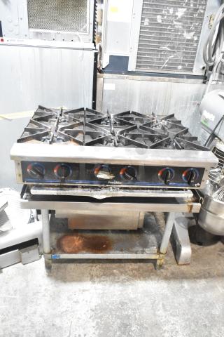Star Max stainless steel 6-burner gas range on equipment stand; used condition, visible wear on stovetop and stand.