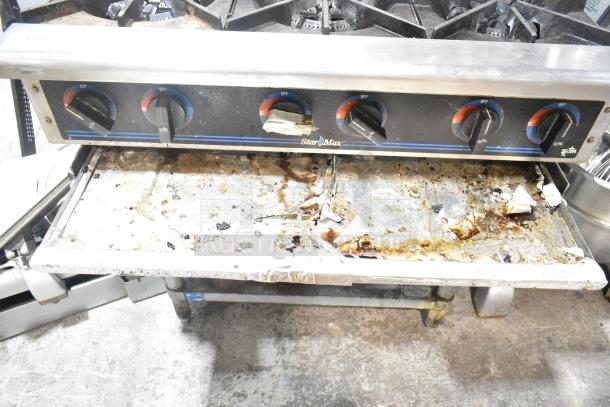 Star Max stainless steel 6-burner gas range on stand, used condition, visible grime and residue, suitable for commercial use.
