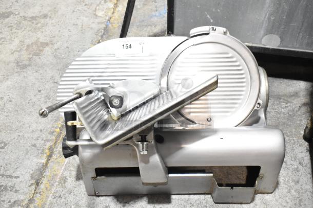 Commercial countertop meat slicer, metal build, 115 volts, 1 phase. Features ribbed blade, handle, and base. Used condition.