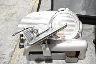 Commercial countertop meat slicer, metal build, 115 volts, 1 phase. Features ribbed blade, handle, and base. Used condition.