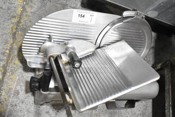 Metal commercial countertop meat slicer, 115 volts, 1 phase. Features a grooved cutting surface, good condition.