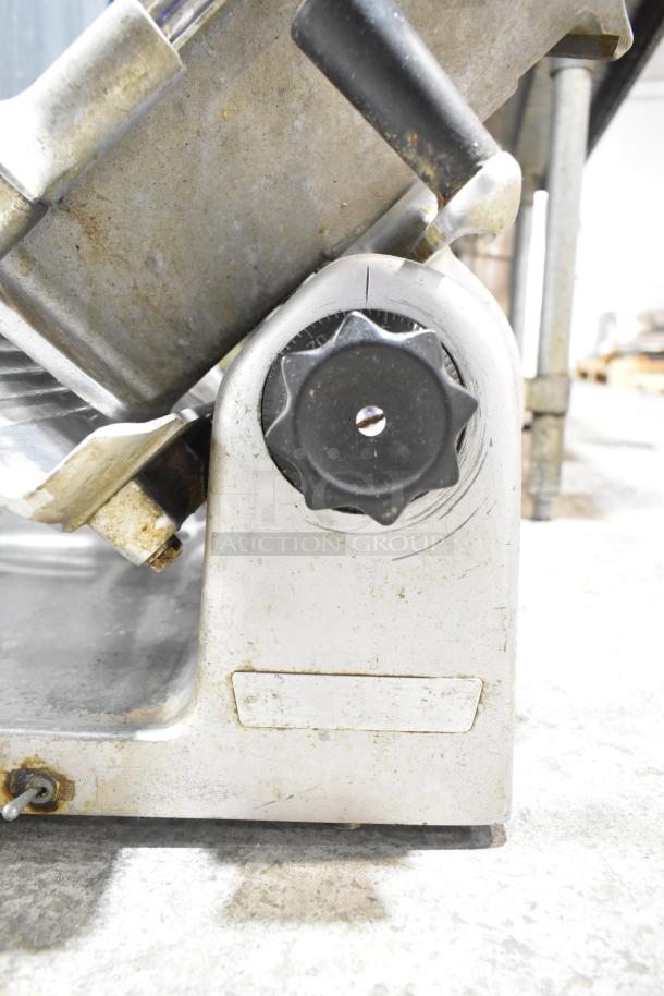 Metal commercial countertop meat slicer, adjustable knob, 115 volts, 1 phase, showing signs of use.