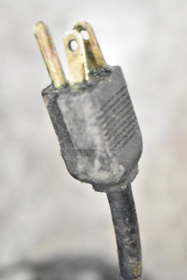 Alt text: Close-up of a worn electrical plug for a metal commercial countertop meat slicer, 115 volts, 1 phase.