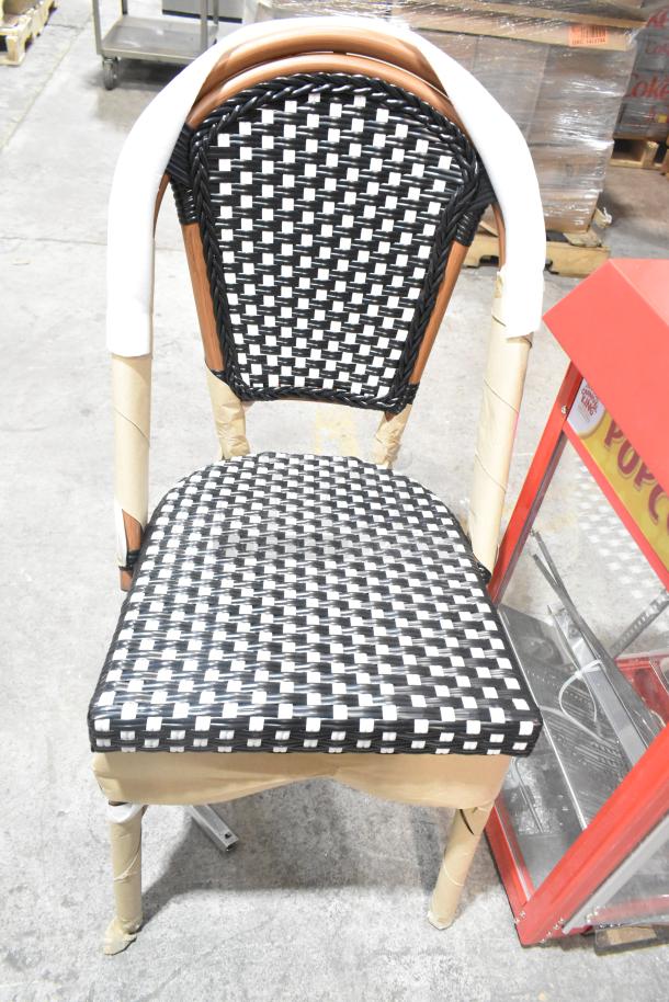 Brand new wicker style chair with black and white woven pattern, protective wrapping on frame, scratch and dent condition.