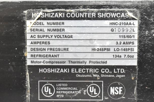 Hoshizaki HNC-210AA-L sushi display case label, shows model, voltage (115V), current (3.2A), refrigerant type (R134a), and certifications.