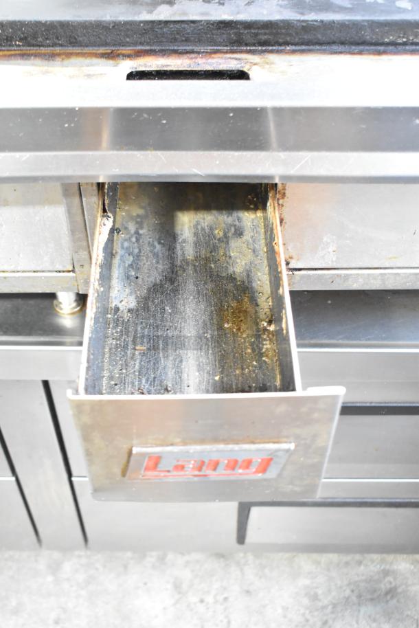 Lang stainless steel commercial griddle with thermostatic controls, visible drawer, and brand label. Moderate wear.