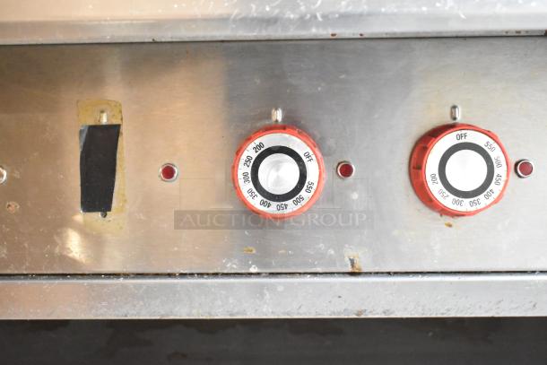 Lang stainless steel commercial griddle controls, featuring two red thermostatic knobs on a stainless steel chef base.