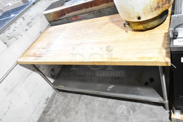 Wooden butcher block table with metal under shelf, showing wear. Ideal for kitchen prep. Marks suggest previous use.