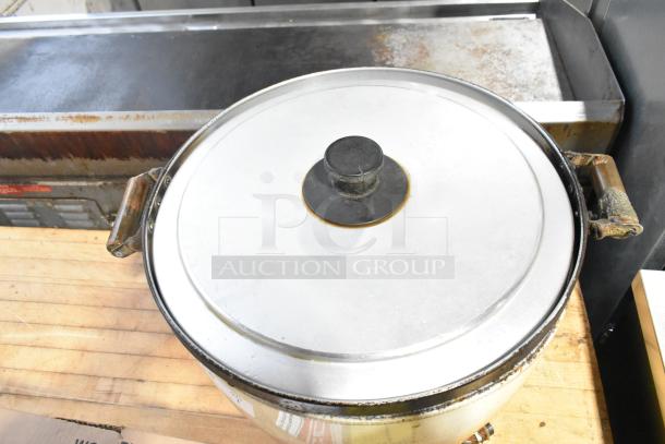 Metal countertop rice cooker with large capacity and sturdy handles. Visible wear on handles, used condition.
