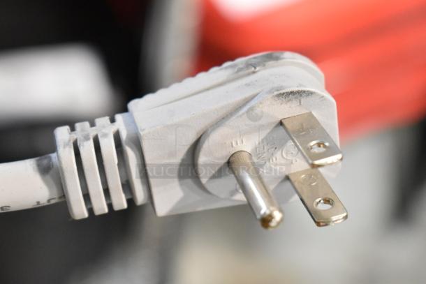 Close-up of a power plug with visible markings, connected to a 2025 Amana RCS10TS commercial microwave.