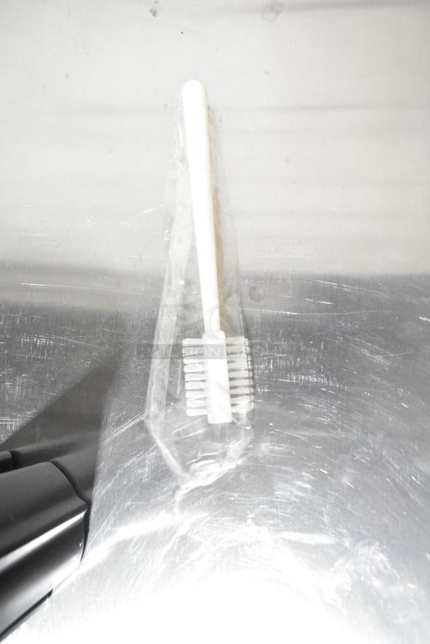 Plastic-packaged cleaning brush accessory for AvaMix 928JE700 Juice Extractor, displayed on a stainless steel surface.