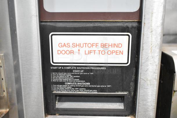 Baxter stainless steel mini rotating rack oven, natural gas powered, on double pan rack with commercial casters. 95,000 BTU. Gas shutoff label visible.