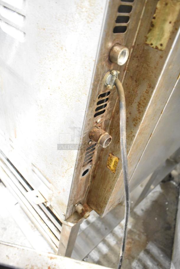 Baxter stainless steel rotating rack oven, natural gas powered, visible gas supply inlet, on double pan rack with casters.