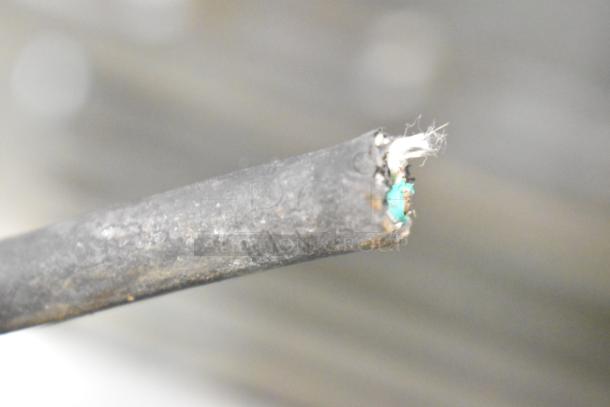 A close-up of a frayed cable end with exposed green and white wires, showing signs of wear.