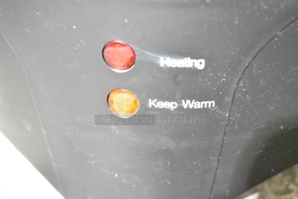 "Heating" and "Keep Warm" indicator lights on black surface with textured background.