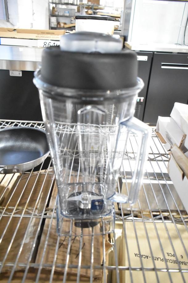 Brand new kitchen items including a clear handled blender jar and non-stick pan on metal shelf. Ideal for auctions.