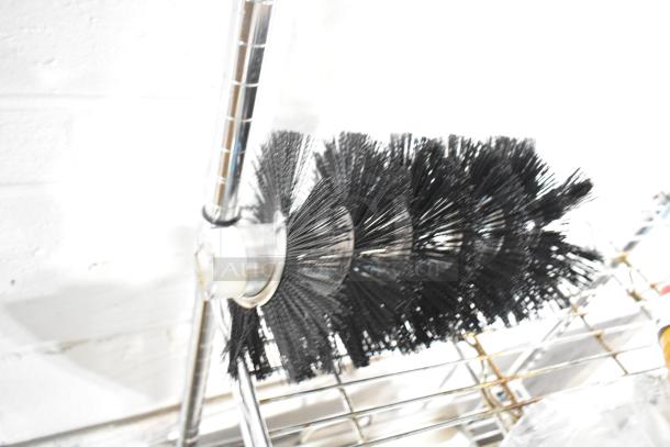 Close-up of a new cleaning brush with black bristles on a metal rod, part of a scratch and dent auction lot.