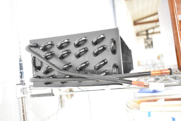 Brand new 2025 ARC-270Y/Z evaporator coil with minor scratches, black with visible tubing, on metal shelving.