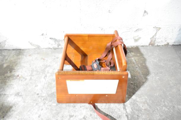 BRAND NEW SCRATCH AND DENT! GET BS-200-MOD-W2 walnut wood booster seat with T-strap, visible tag with safety warning.