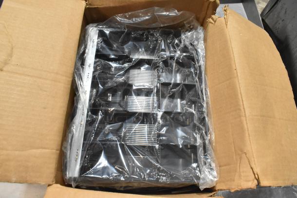 Box containing three brand new cash drawer inserts wrapped in plastic inside an open cardboard box.