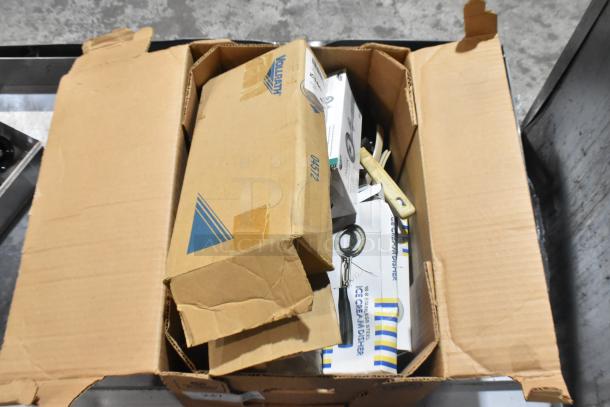 Box containing brand new Vollrath 4780912 tongs, scoopers, and dippers. Condition is pristine with packaging visible.