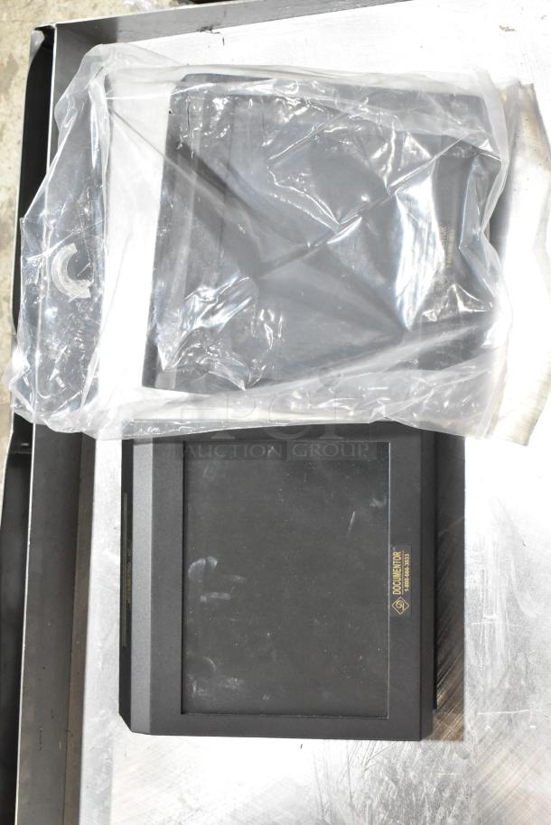 Two TPOS1225 monitors, one in a plastic cover, on a metallic surface. The visible label reads "Document Top." Good condition.