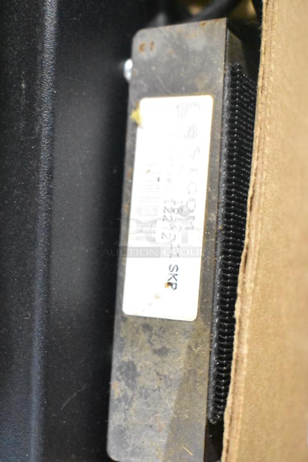 Close-up of a component with a "SICOM" label, part of an auction lot including 7 POS monitors and receipt printers.