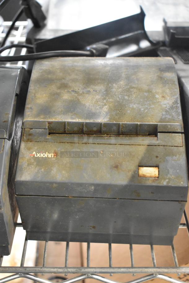 Aged Axiohm receipt printer, visible wear and rust, on metal shelving. Auction lot includes various POS equipment.
