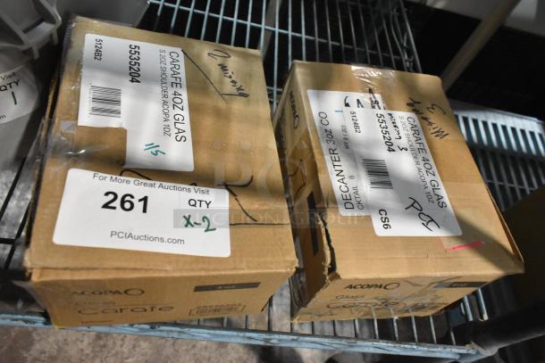 Boxes of Acopa 4 oz. glass carafes, marked "Scratch and Dent," new condition, labeled with auction info "x2."