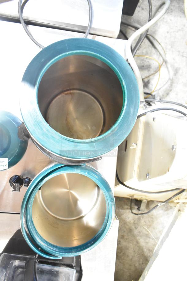 Two metal beverage holder dispensers with open tops, green rims, and stainless steel interiors, in used condition.