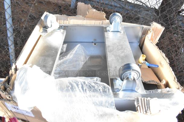 Stainless steel mobile ice bin with wheels, new condition, in packaging. Includes additional items and components.