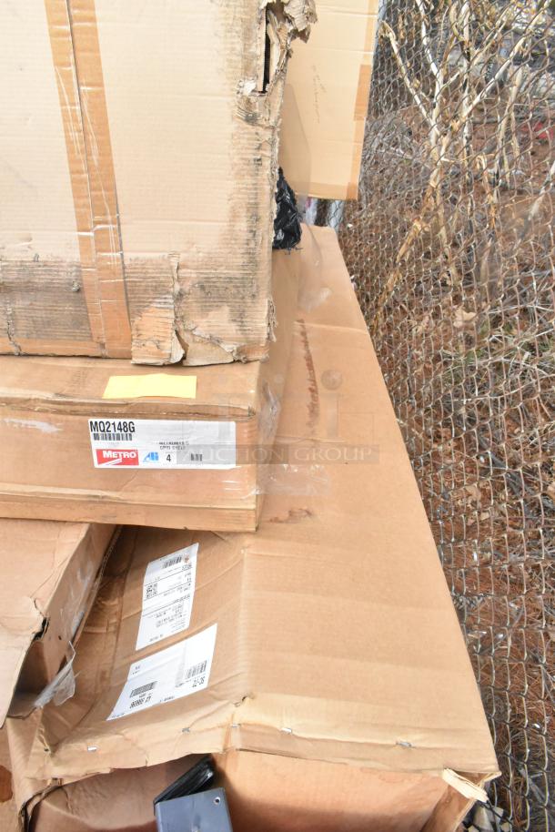 Cardboard boxes containing new Krowne KR24-HX18 dual sink, Metro MQ2148G shelf, SC-72 pot rack. Boxes show wear.