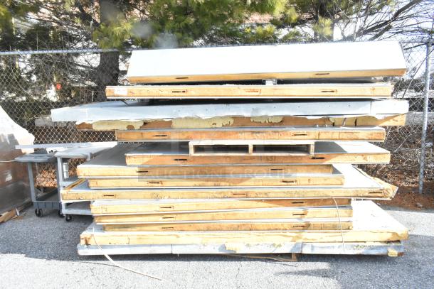 Stack of walk-in box panels, no compressor or condenser, shown outdoors; worn edges, insulation visible.