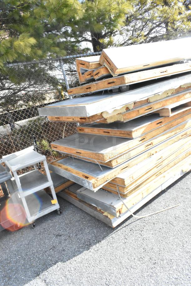 Stack of insulated panels for a walk-in box without compressor or condenser, showing wear, ideal for cold storage setup.