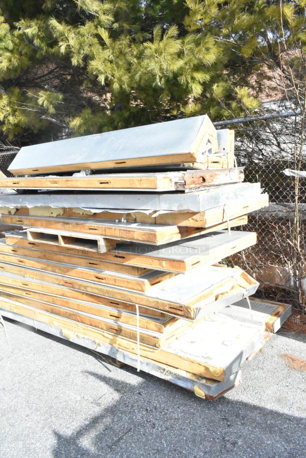 Stacked walk-in box panels without compressor or condenser, showing metallic surfaces and insulation. Weathered condition.