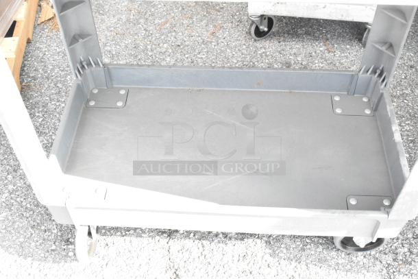 Two gray poly 3-tier carts on commercial casters, sturdy and versatile for various uses, in good condition.